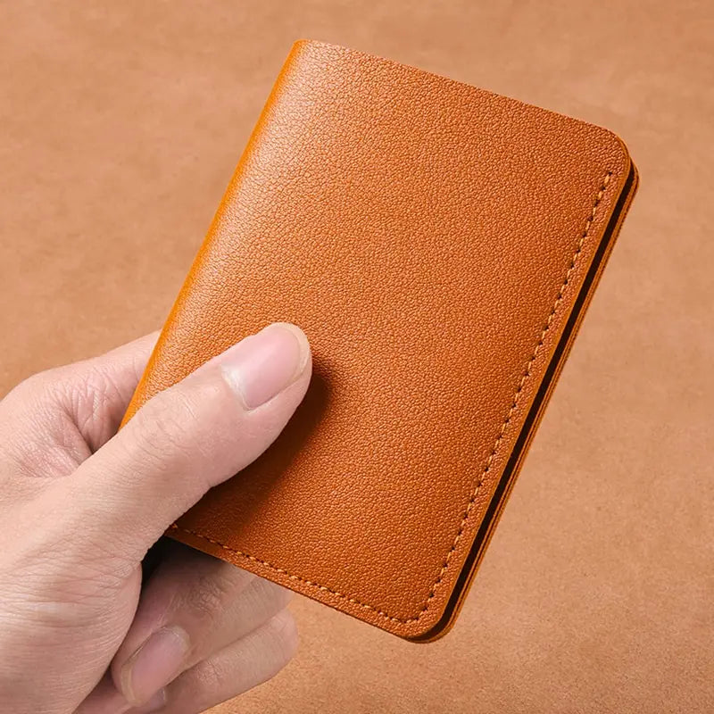 A hand holds an orange brown ultra-thin PU leather compact wallet against a plain brown background.