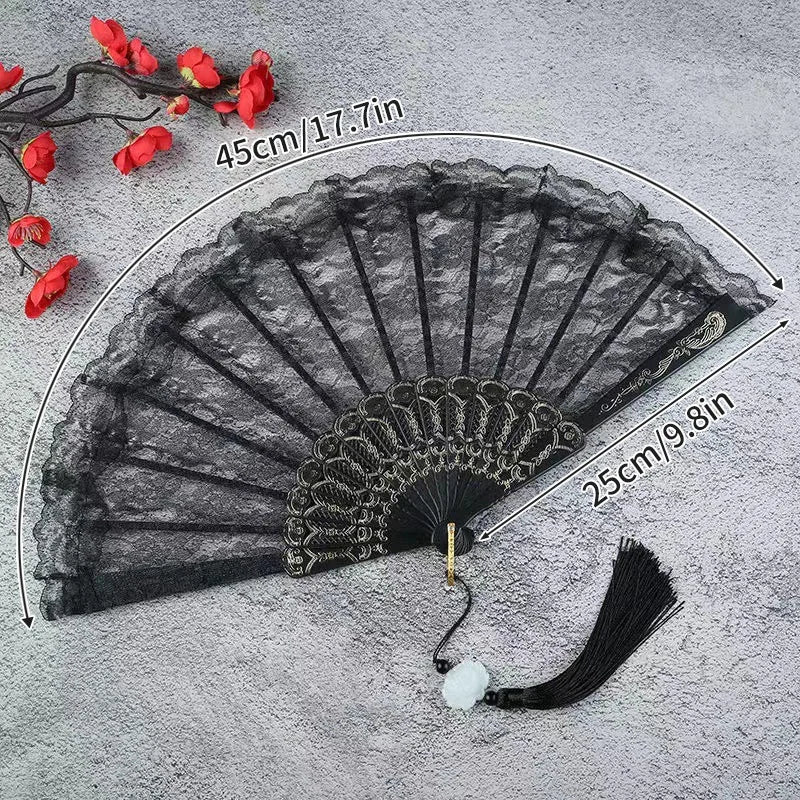 Black lace-trimmed folding fan with a golden edge displayed on a gray surface.