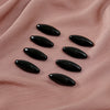 A set of eight black, oval-shaped scarf pins resting on a soft pink fabric.
