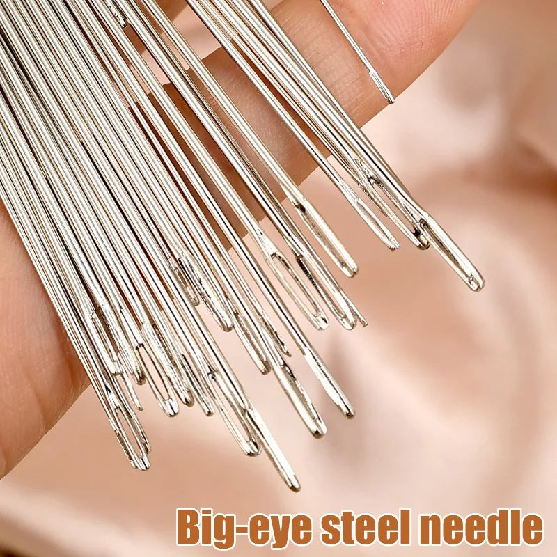 A hand holds a bundle of big-eye steel sewing needles.