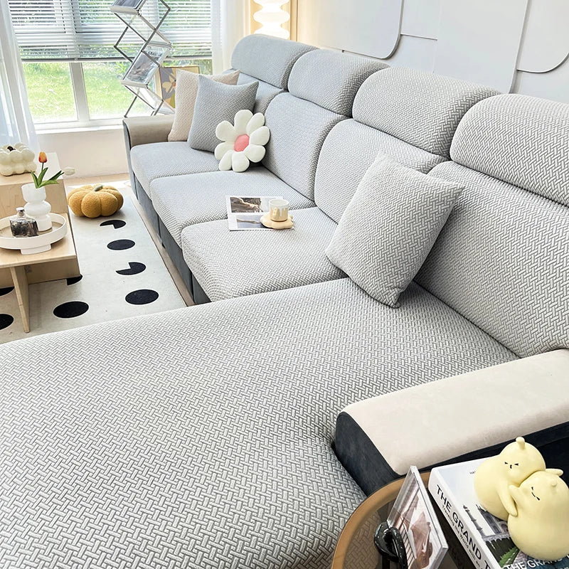 A light gray elegant jacquard sofa slipcover with an elastic fit shown in a bright, modern living room.