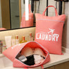 A pink laundry bag is displayed on a counter next to a mirror, with other bags and a hairdryer visible.