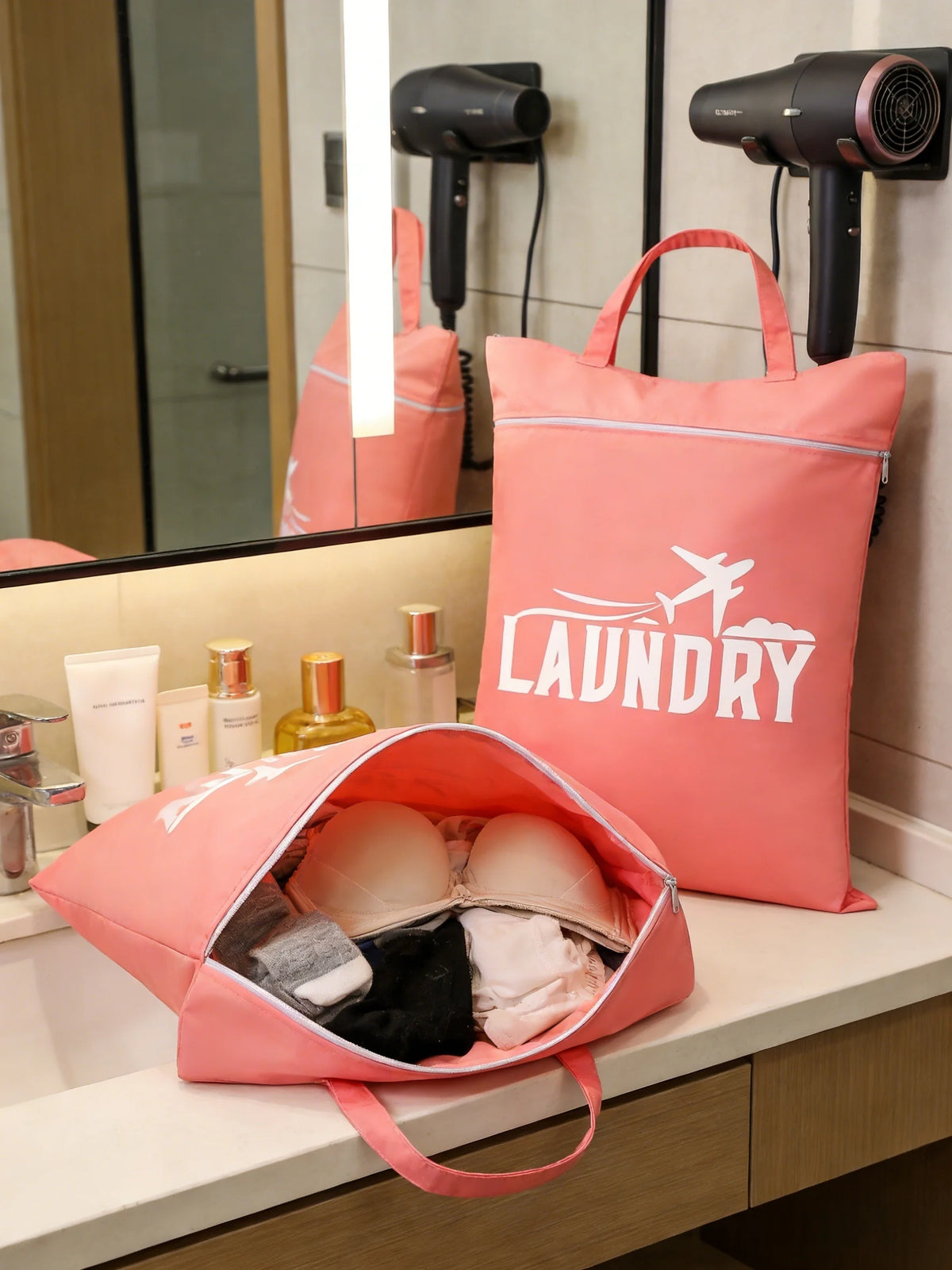 A pink laundry bag is displayed on a counter next to a mirror, with other bags and a hairdryer visible.