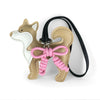 A tan and white Shiba Inu PU leather bag charm with a pink braided bow on a black strap.