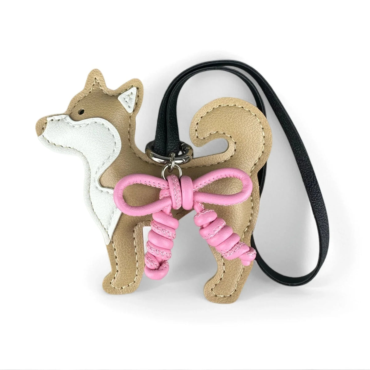 A tan and white Shiba Inu PU leather bag charm with a pink braided bow on a black strap.