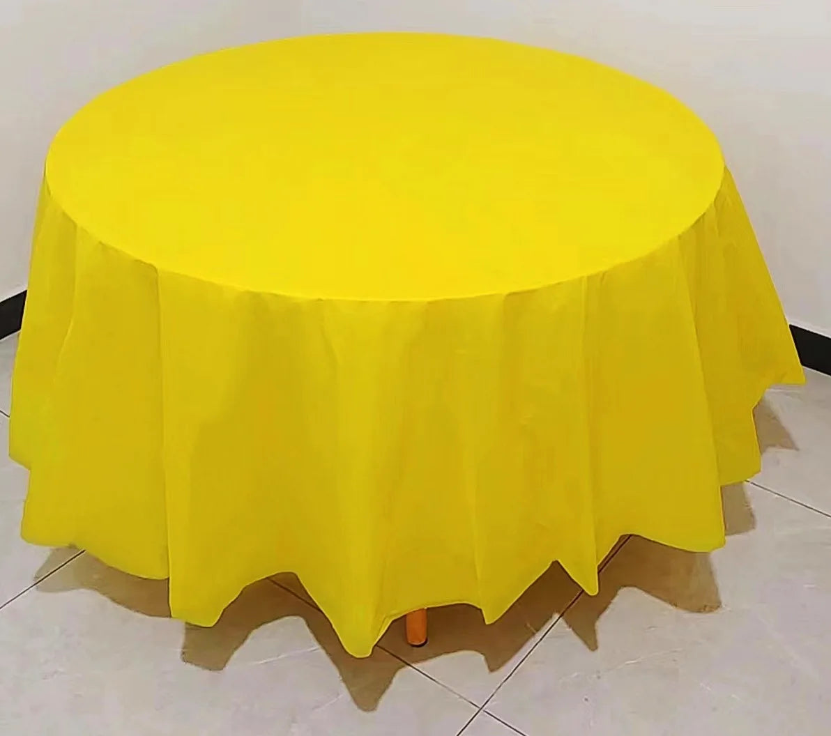 A bright yellow disposable round tablecloth is displayed on a table.