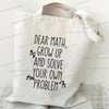 A white canvas tote bag with black text that reads Dear Math Grow Up and Solve Your Own Problem