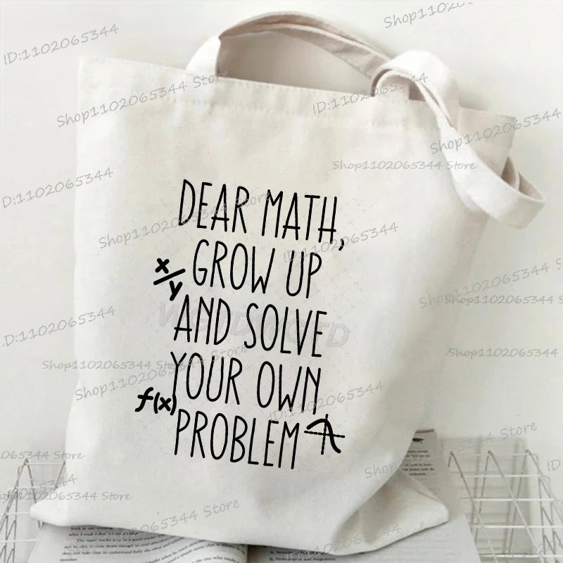 A white canvas tote bag with black text that reads Dear Math Grow Up and Solve Your Own Problem