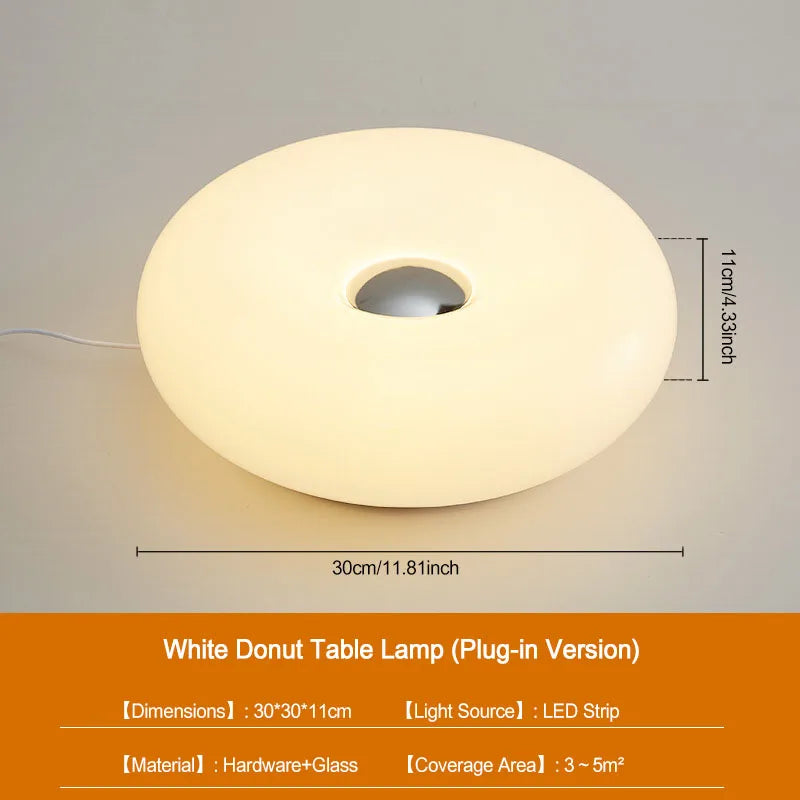 A white donut-shaped plug-in table lamp with a diffused light source.
