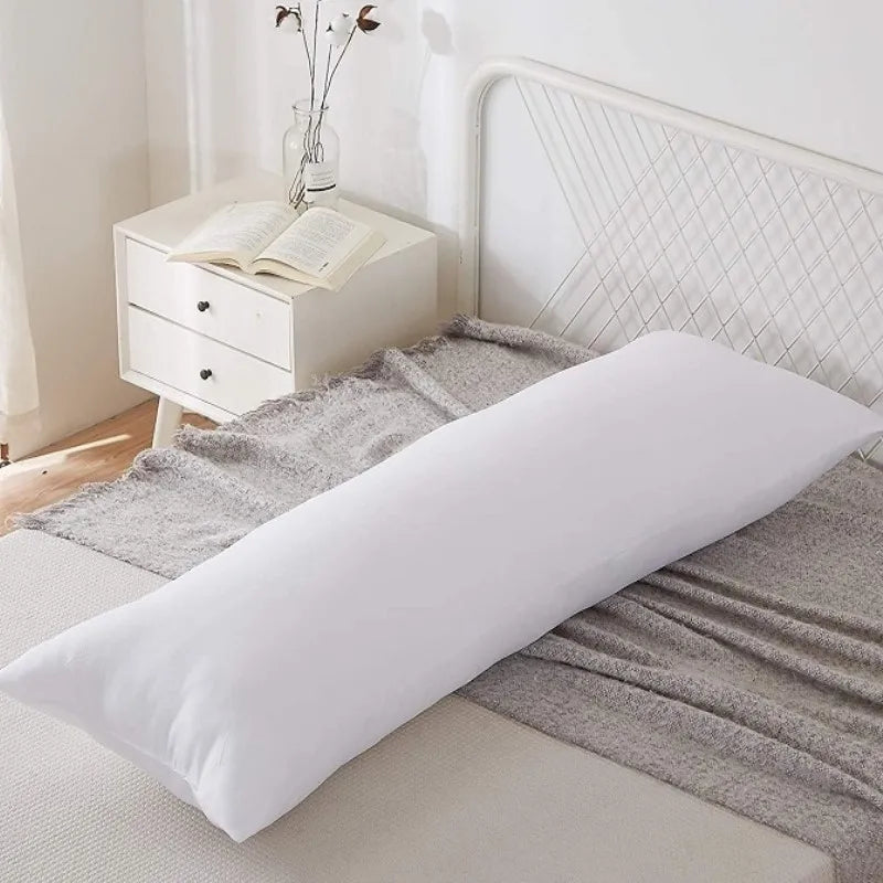 A white square cushion placed on a gray blanket in front of a white metal headboard.