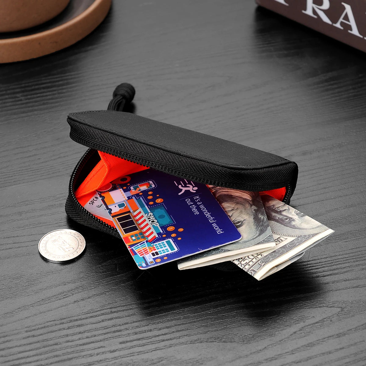 A black compact RFID wallet with an orange lining is shown open on a dark wooden surface.
