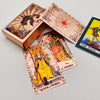 A set of gold foil tarot cards and a guidebook are displayed on a light gray surface.