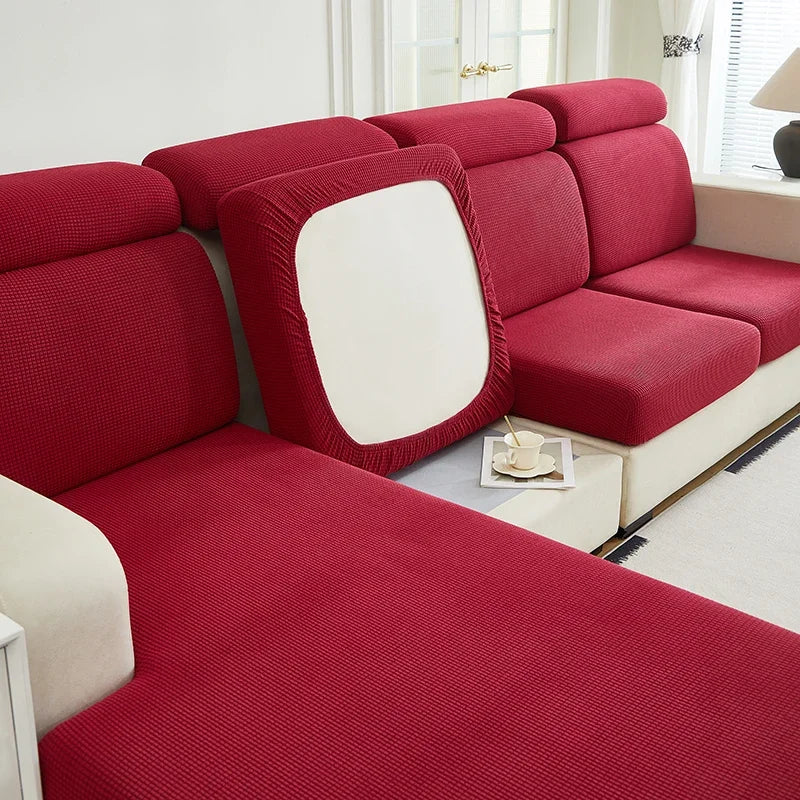 A deep red Jacquard stretch sofa slipcover with a white accent panel shown in a bright room.