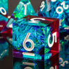 A close-up of a translucent blue resin polyhedral die with the number 6 visible, set against other colorful dice.