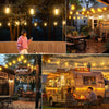 A vintage camper van is decorated with solar string lights in an outdoor setting.