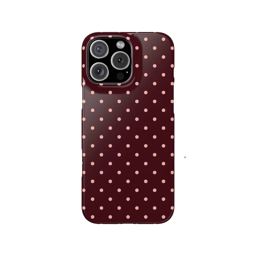 A dark maroon phone case for an iPhone featuring a pattern of small, light pink polka dots.