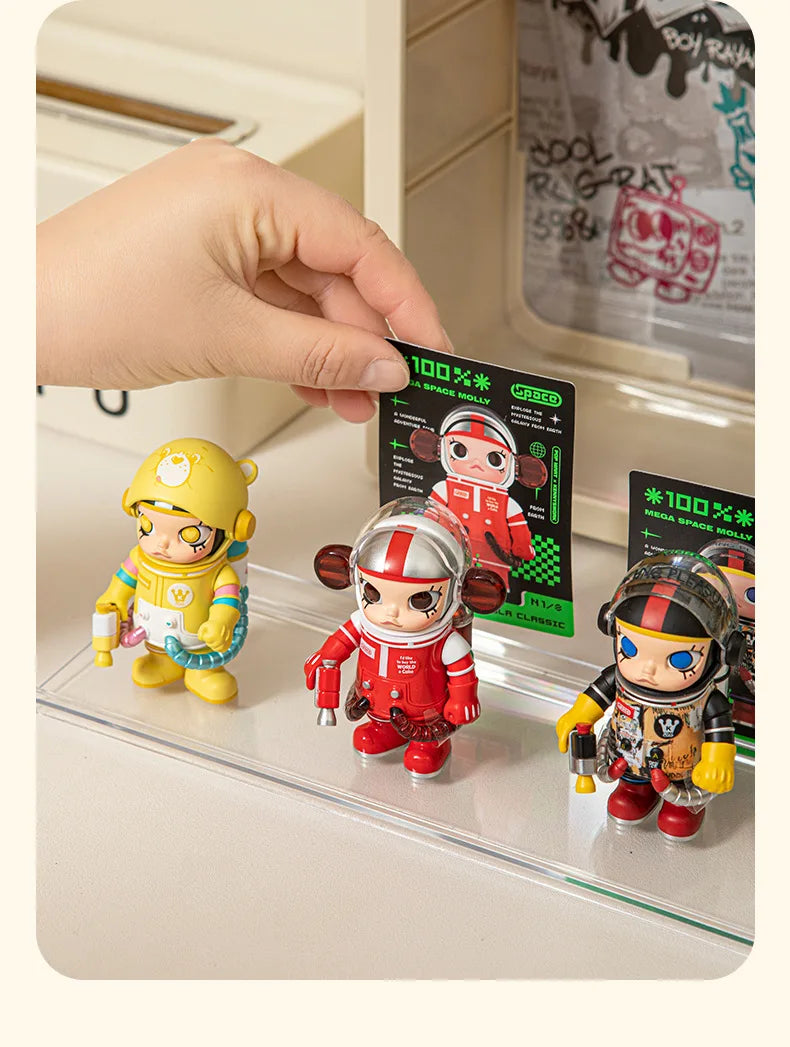 A hand places several collectible dolls, including a yellow and red figure, into a wall-mounted dustproof display case.