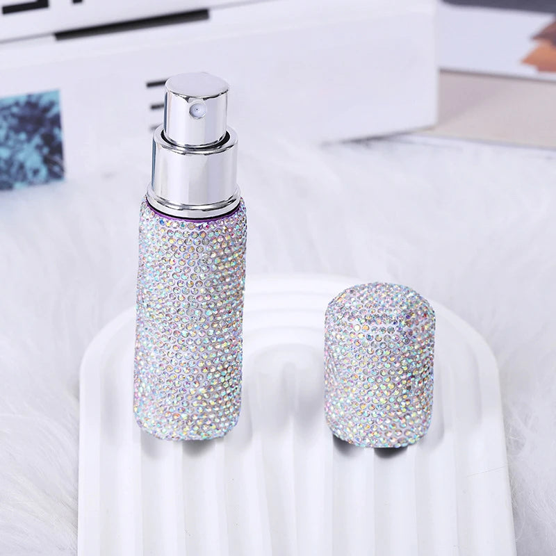 A silver glass perfume atomizer with a purple glitter body is displayed on a white surface.