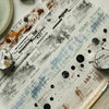 Decorative PET washi tape featuring a mottled collage design with black and white markings on a light background.