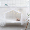 A white princess-style lace canopy mosquito net draped over a bed frame with string lights.