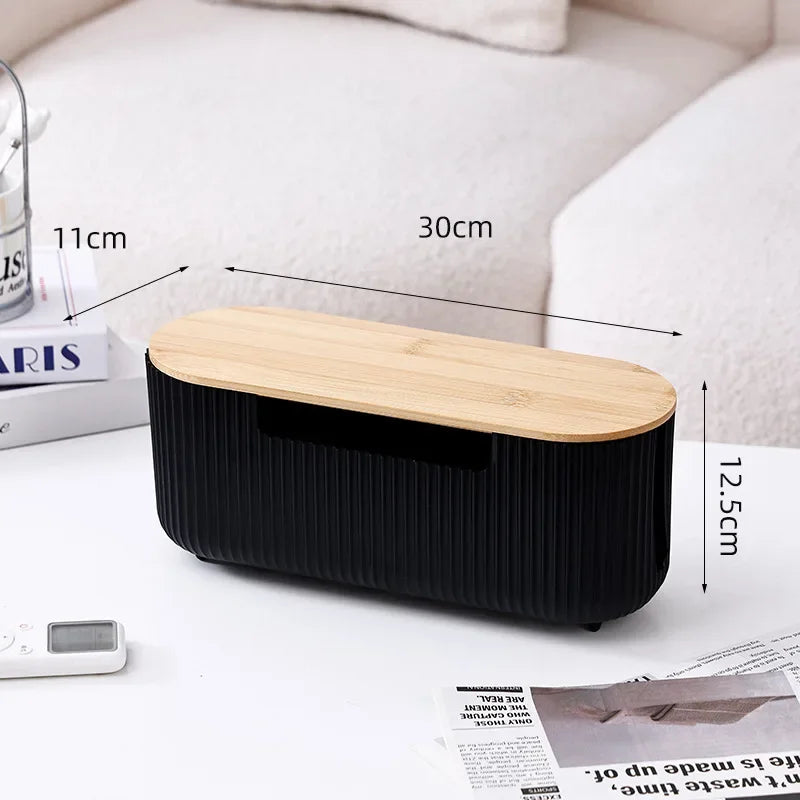 A black cable management box with a wooden lid is shown on a white desk surface.