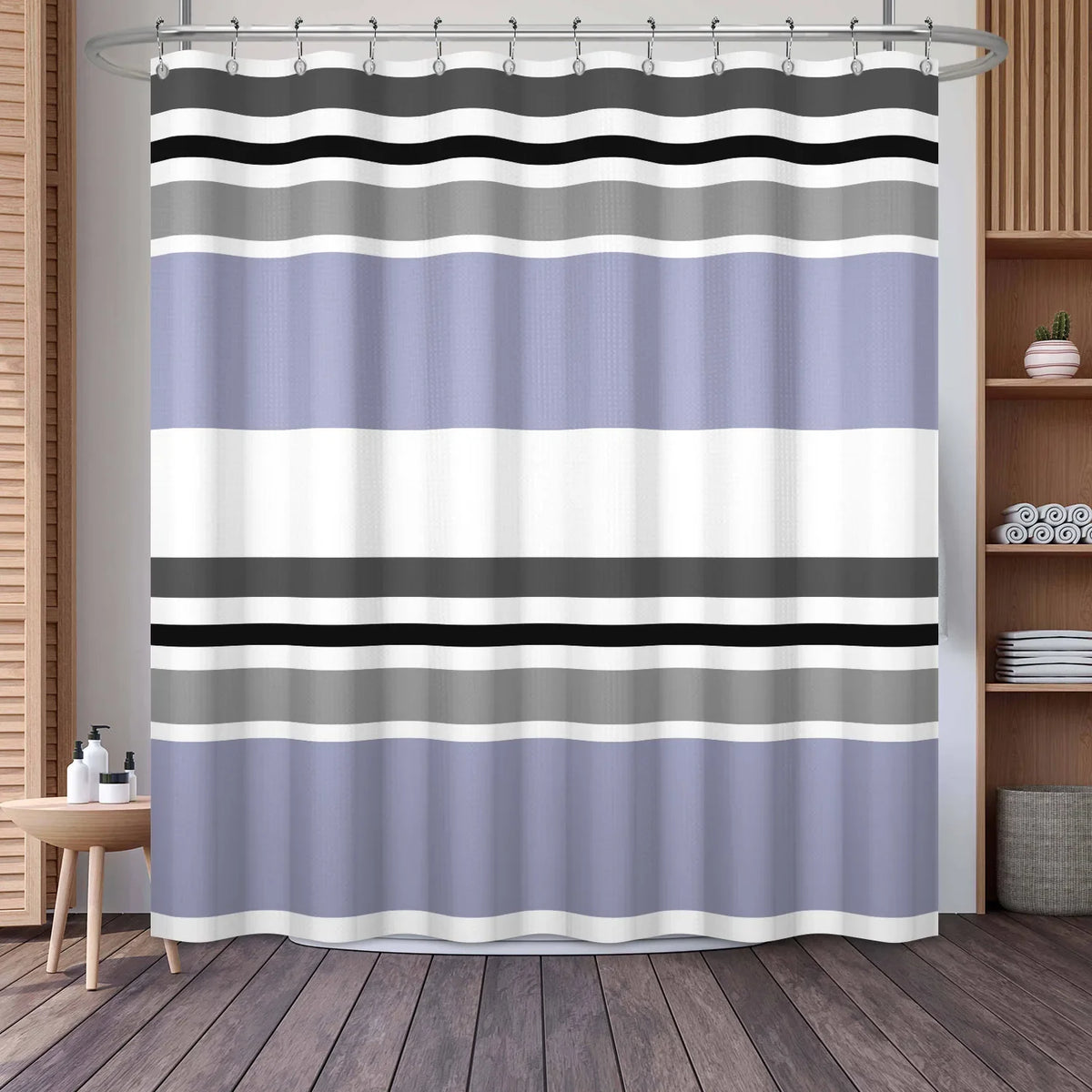 A shower curtain featuring horizontal geometric stripes in shades of gray, black, and light purple on a rod.