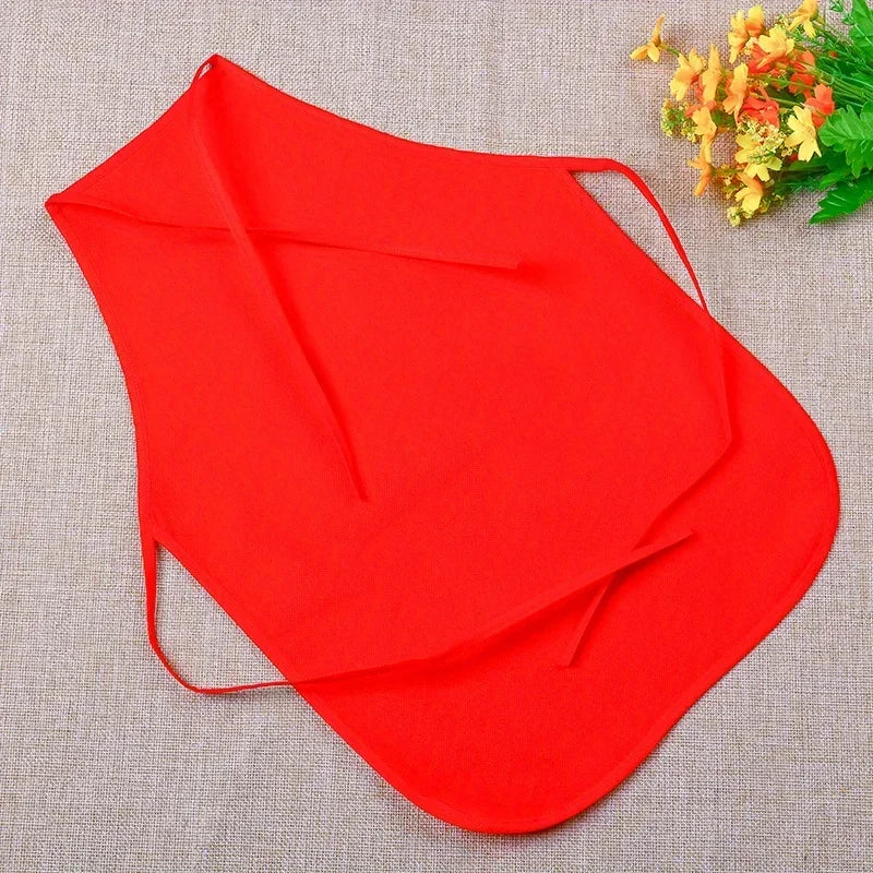 A bright red non-woven fabric craft apron is shown against a beige background with a small yellow floral arrangement.