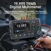 A hand is using an FNIRSI digital multimeter on a car engine component.