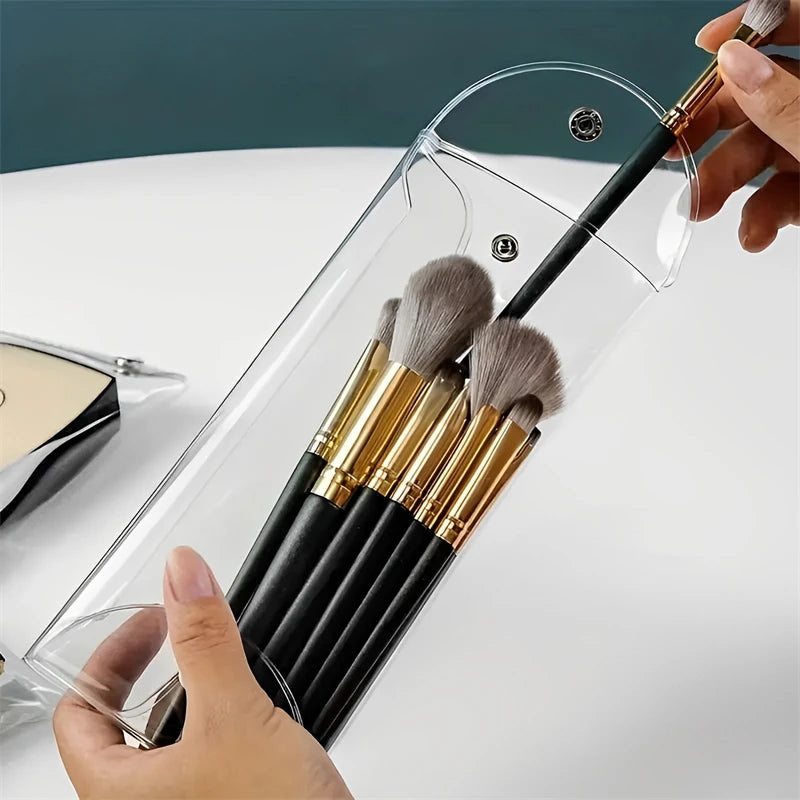 A hand is inserting makeup brushes into a transparent PVC cosmetic bag for waterproof storage.