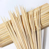 A bundle of natural bamboo skewers laid out diagonally against a white background.
