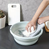 A hand is using a white non-slip laundry scrubbing board to clean a white bowl of water.