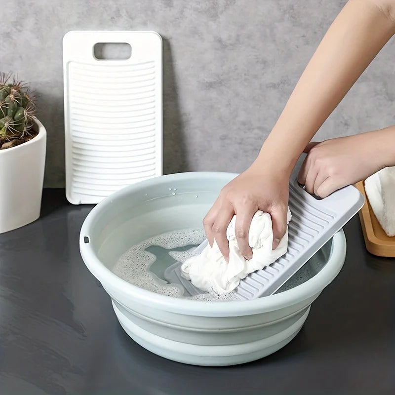 A hand is using a white non-slip laundry scrubbing board to clean a white bowl of water.