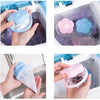 Hands holding pink and blue silicone filter bags for washing machine lint and hair catcher.
