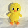 A yellow, fluffy plush toy resembling a chick or small animal with large eyes and orange feet.