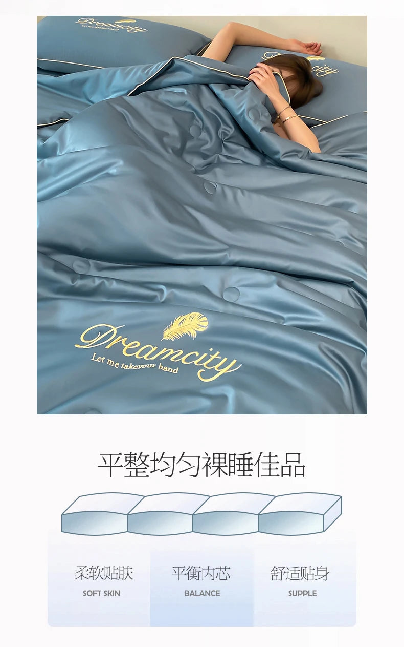 A light blue comforter with embroidered text on a bed, showcasing soft skin, balance, and supple texture.