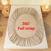 A beige fitted bed sheet is shown fully wrapped around a mattress, demonstrating a 360 degree coverage.