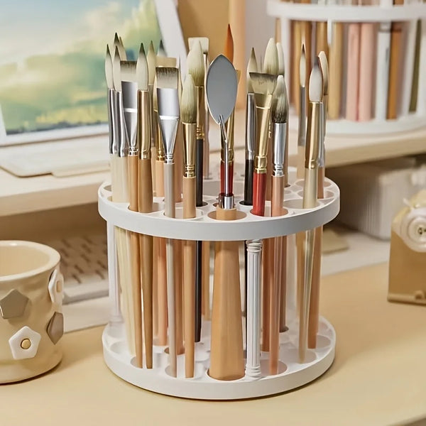 Support rotatif blanc pour pinceaux et outils d'art sur un bureau en bois.