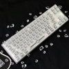 A translucent PC keycap for a mechanical keyboard lying on a black surface with scattered clear crystals.