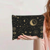 A hand holds a black canvas charger storage pouch decorated with gold celestial designs like the moon and stars.