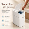 A white touchless lid opening trash can with a sensor, shown in use on a countertop.