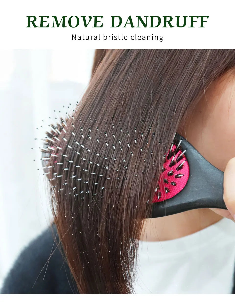A person is using a black hair brush with natural bristles to clean dandruff from dark brown hair.