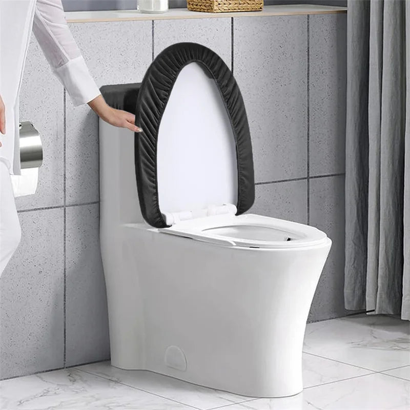 A white toilet with a black stretchable seat and tank cover installed in a bathroom setting.