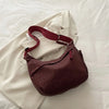 A deep burgundy leopard print crossbody bag resting on a white fabric background.