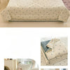 A light beige quilt with a subtle blue cartoon pattern featuring small animals, displayed on a bed.