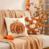 A set of vintage fall pumpkin pillow covers in orange and cream on a beige knitted blanket.