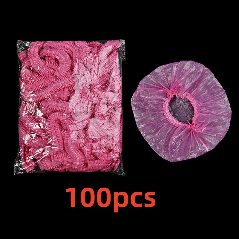 A package of 100 pink disposable shower caps for hair protection and salon use.
