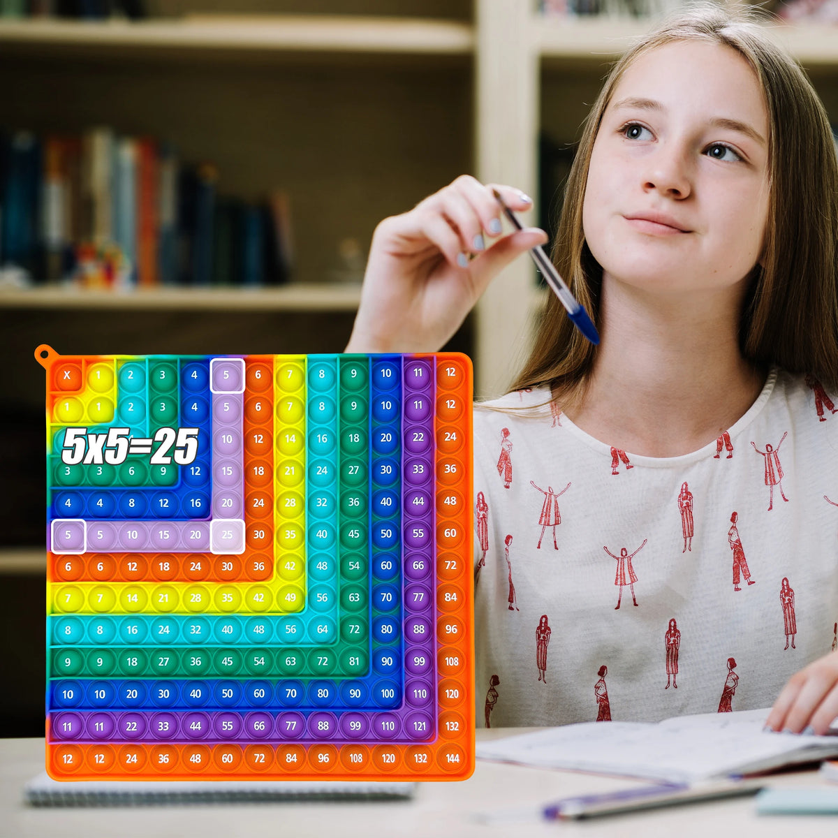 A girl is looking at a colorful 12x12 multiplication practice math game board for times table learning.