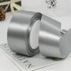 A roll of silver satin ribbon used for gift wrapping and DIY crafts.