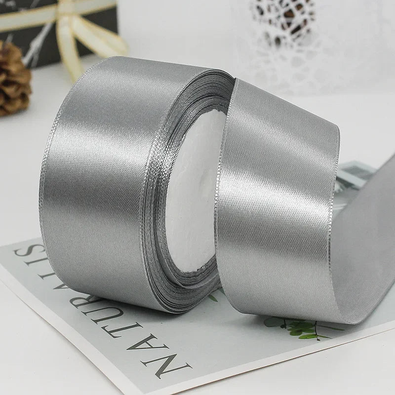 A roll of silver satin ribbon used for gift wrapping and DIY crafts.