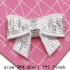 A white sequin bow patch is shown against a pink grid background.